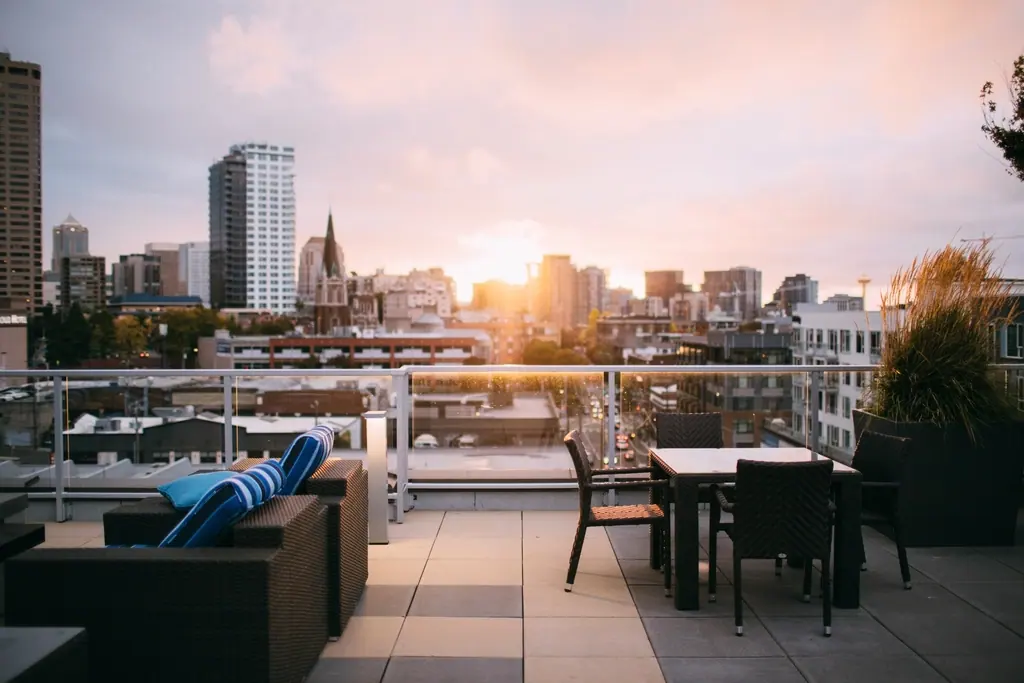 Dachterrasse mit Loungemöbeln und Esstisch bei Sonnenuntergang über der Stadt